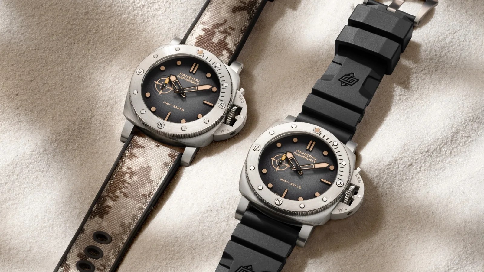 Two Panerai Submersible QuarantaQuattro Navy SEALs watches, one on a digi camo strap and another on a black rubber strap shown at an angle lying on sand