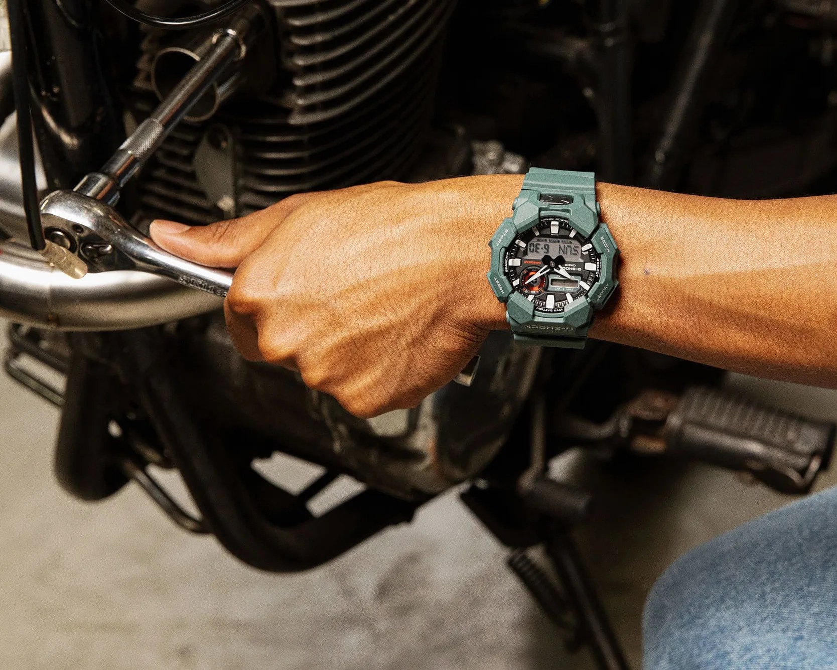 man wearing a g-shock working on a motorcycle