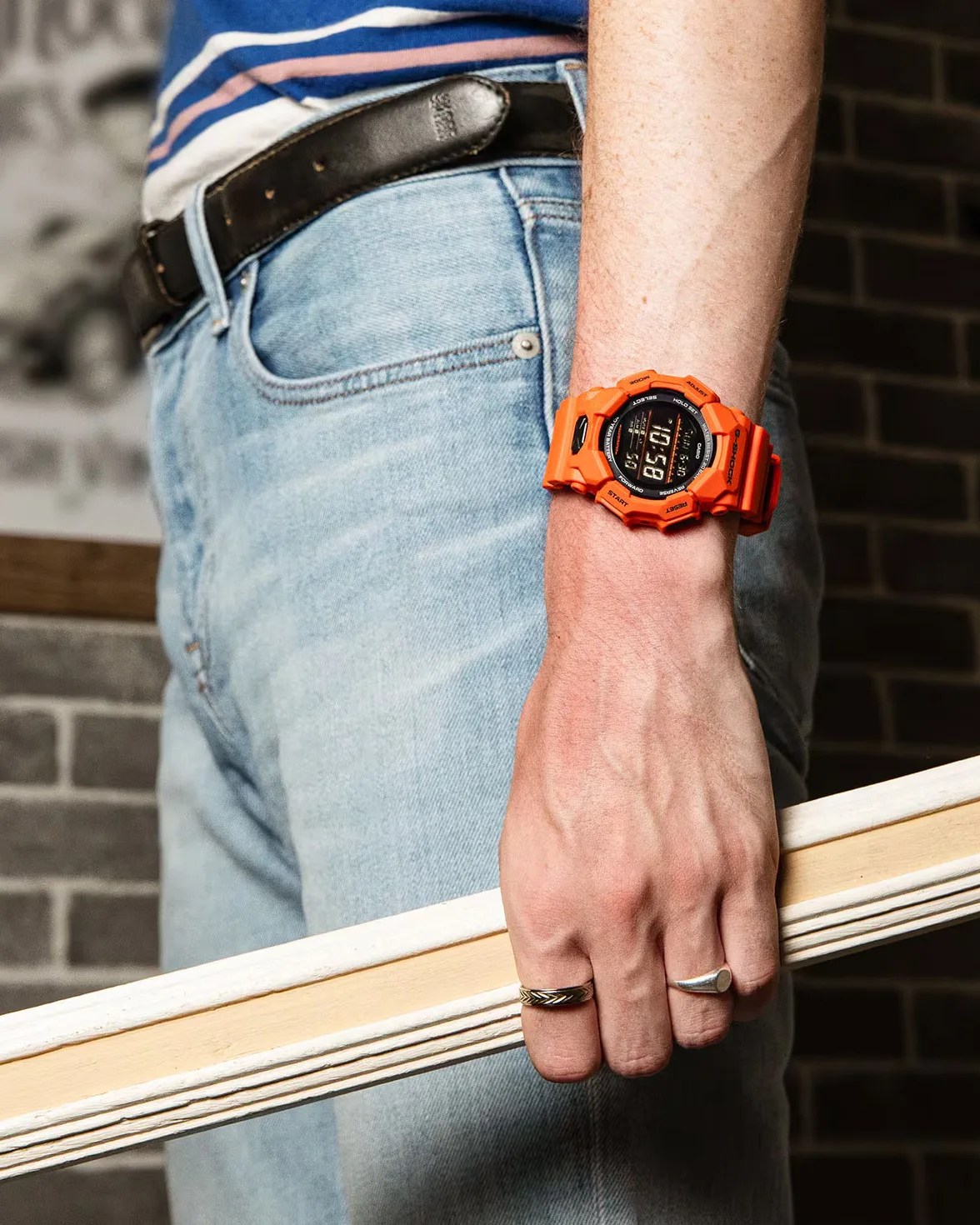 man wearing an orange g-shock watch holding a picture frame