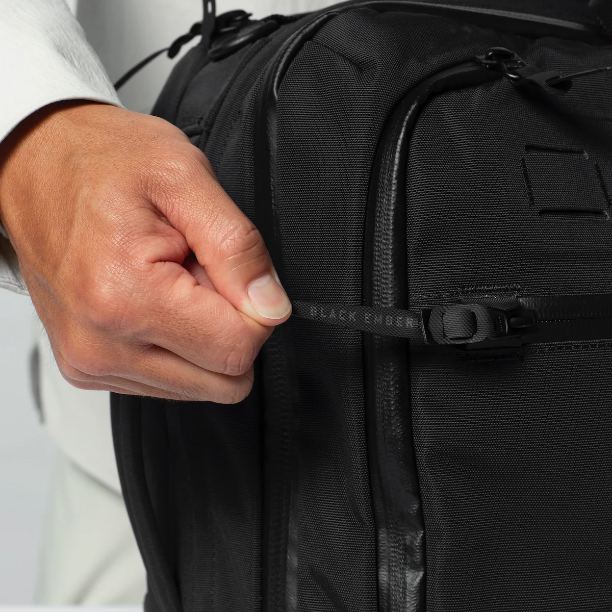 A close up photo of the locking zipper  pulls found on the Black Ember Forge 40 Travel backpack being pulled tight by a hand