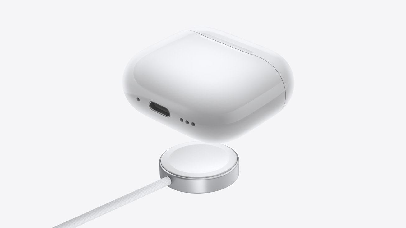 Apple AirPods 4 case hovering over a wired charging puck that allows for wireless charging.