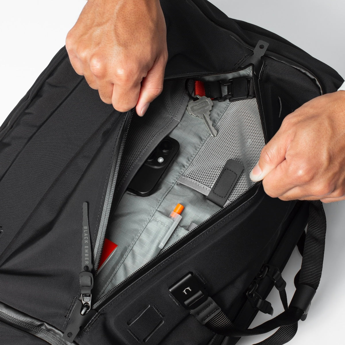 Black Ember Forge 40 travel backpack front zipper pocket opened to reveal dedicated storage slots for an iphone, pens and other smaller items