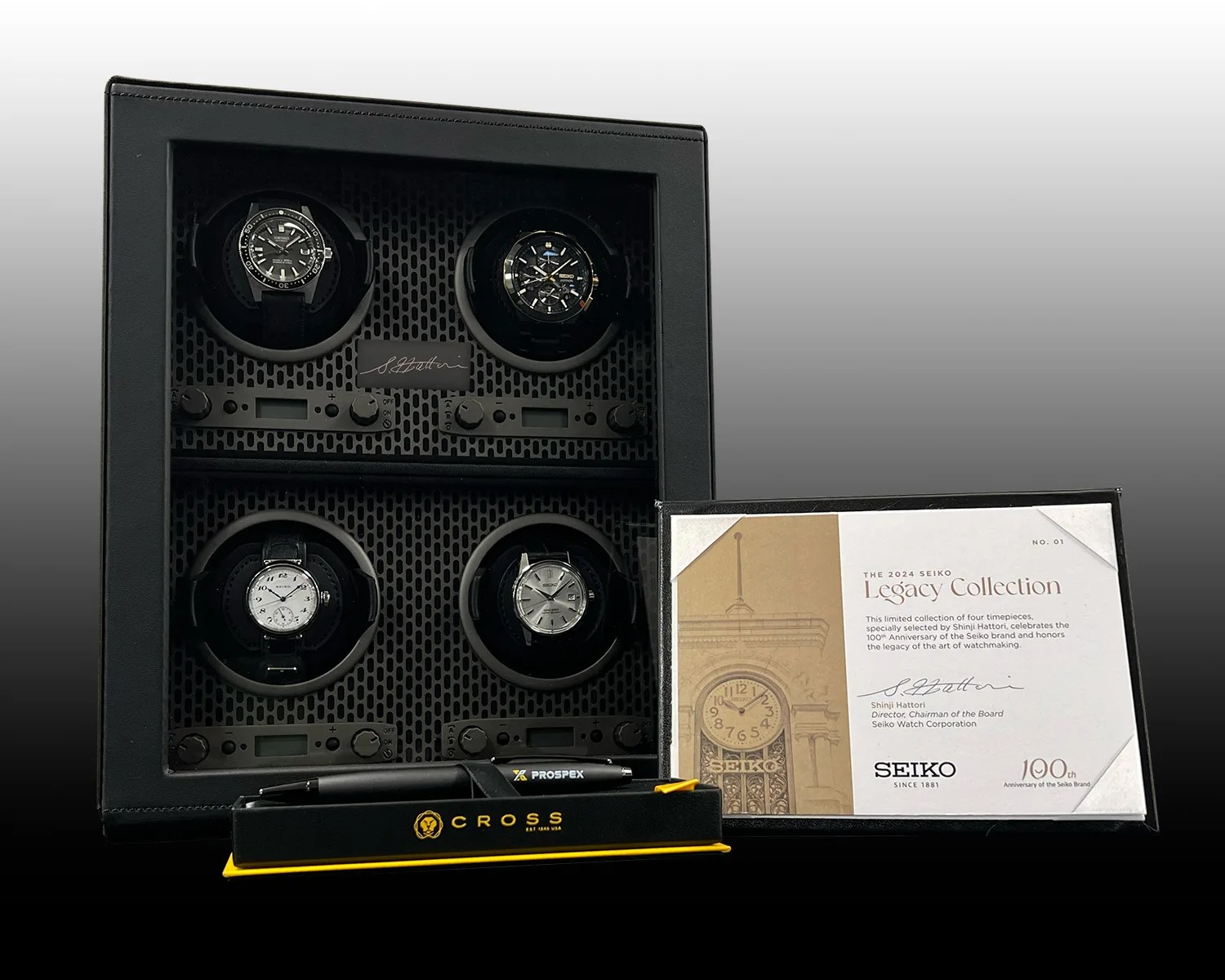 four Seiko watches in a watch winder next to a certificate and a pen