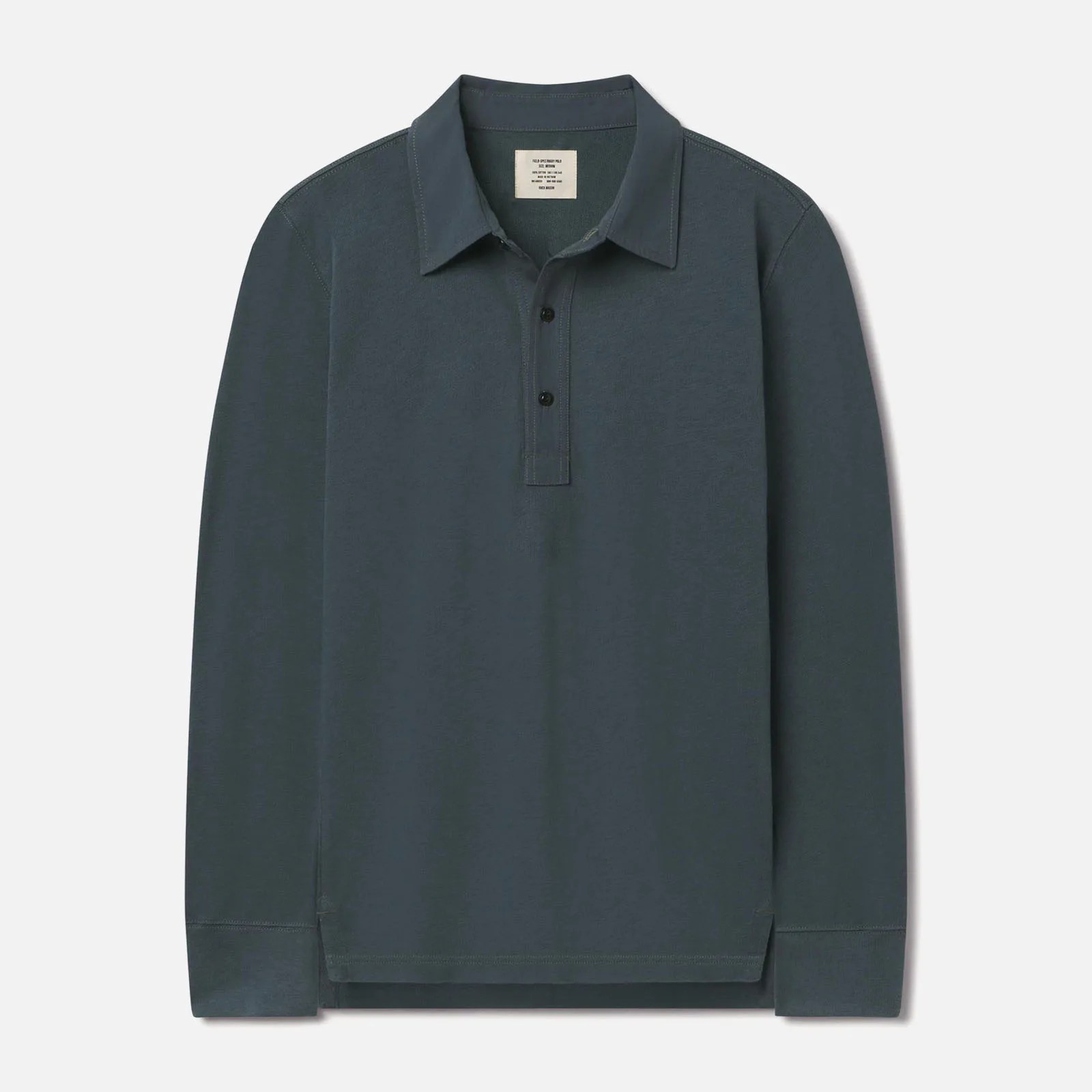 Buck Mason’s Field Spec Rugby shirt in a greenish blue color laid flat against a light grey background