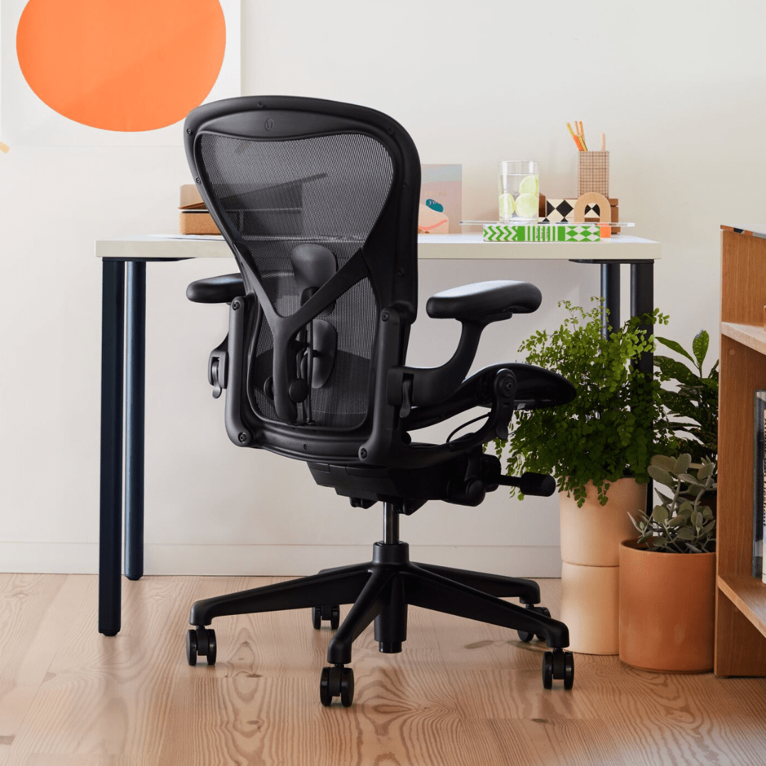 black herman miller office chair facing a white desk