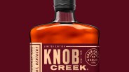 Upper portion of Knob Creek 18 year old bottle down on a red wine colored background