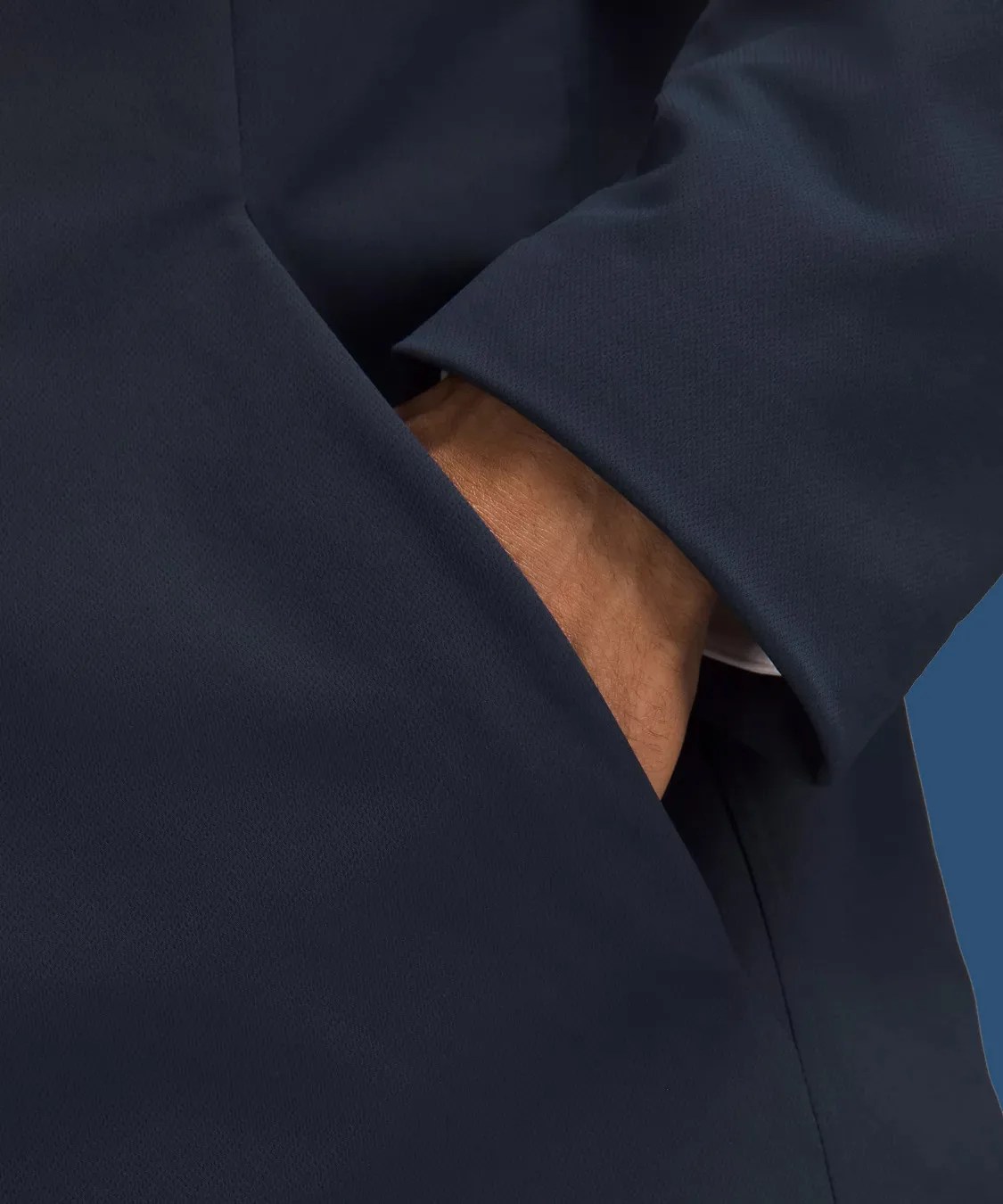 A close up shot of the integrated hand pockets of the Lululemon New Venture Button-Front Blazer. A hand is shown sliding into the navy jackets pocket.  
