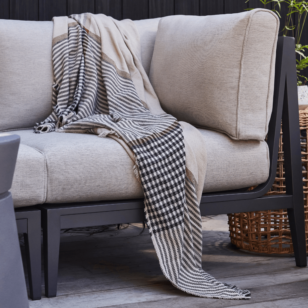 beige black and rust plaid blanket laying on a white outdoor chair