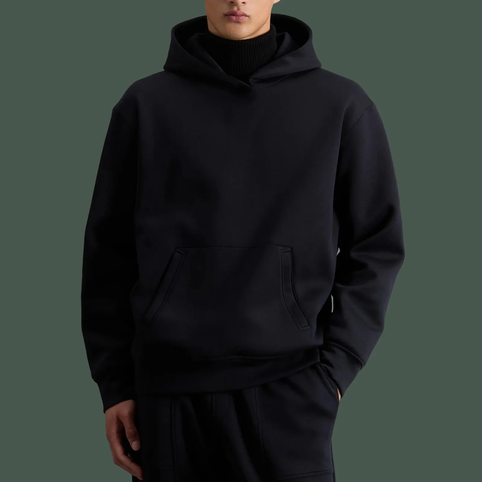 Todd Snyder x Woolrich Luxe Tech Hoodie in black being worn on male model wearing matching black sweatpants standing up with one hand in his pants pocket