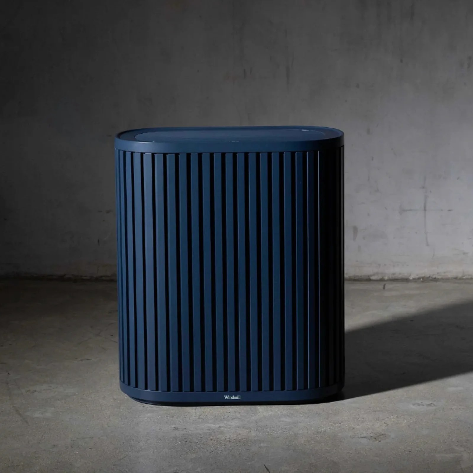 The Windmill Air Purifer in Navy shown sitting on a concrete floor