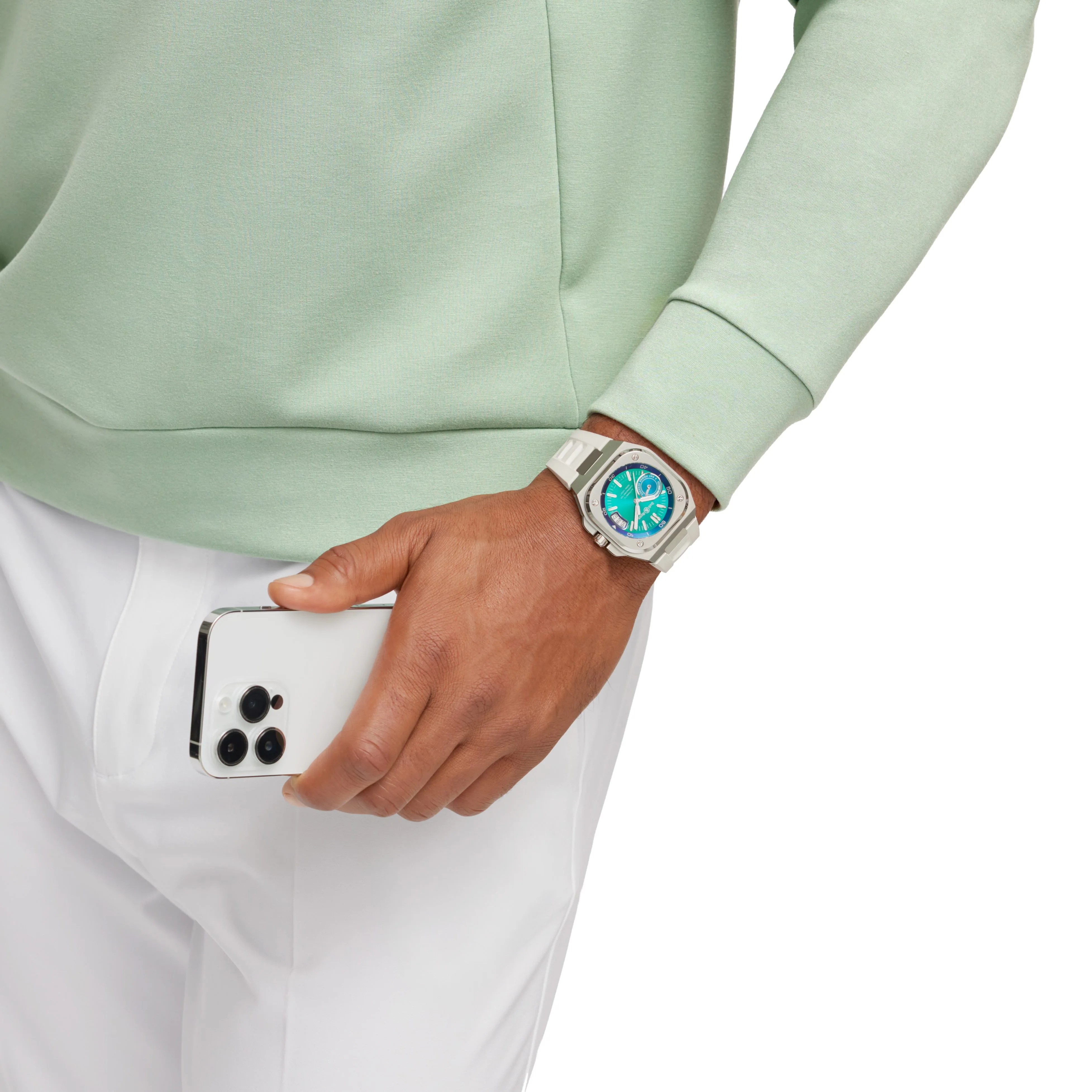 a bell and ross watch worn by a man wearing a green sweatshirt and holding an iphone