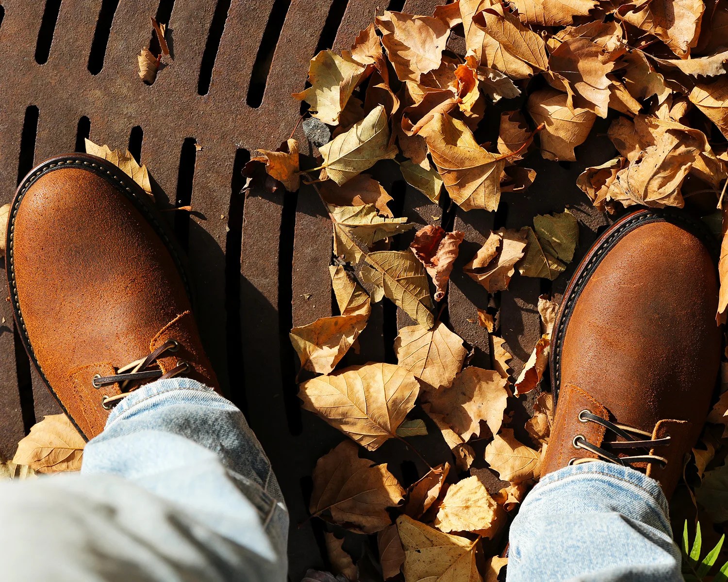 a pair of billy reid x oak street boots on a mans feet standing on leaves