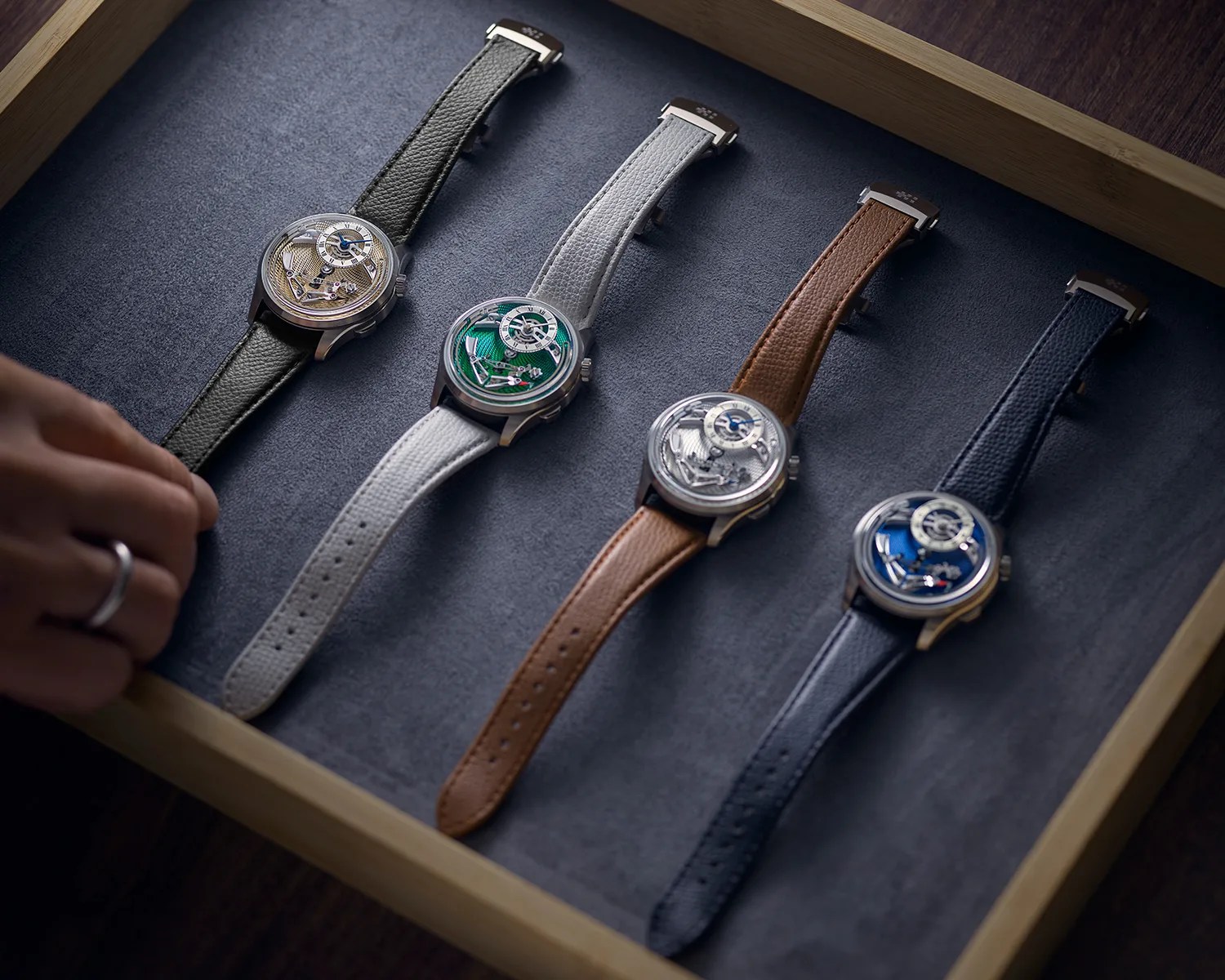 a person selects a watch from a lineup of a christopher ward bel canto watches in a valet tray