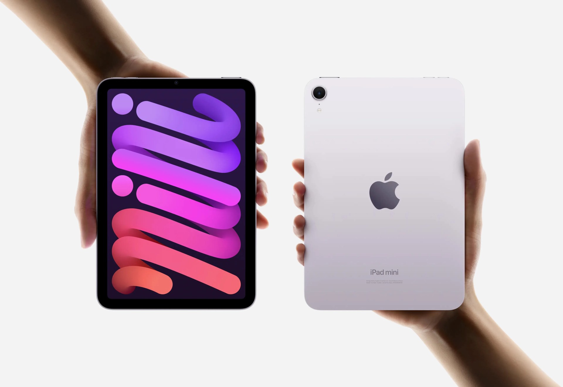 Apple iPad Mini 7th generation shown being held by two hands appearing from different corners of the image. One hand is showing the tablet with the screen facing in the front. The other hand is showing the tablet with the back facing in front. 