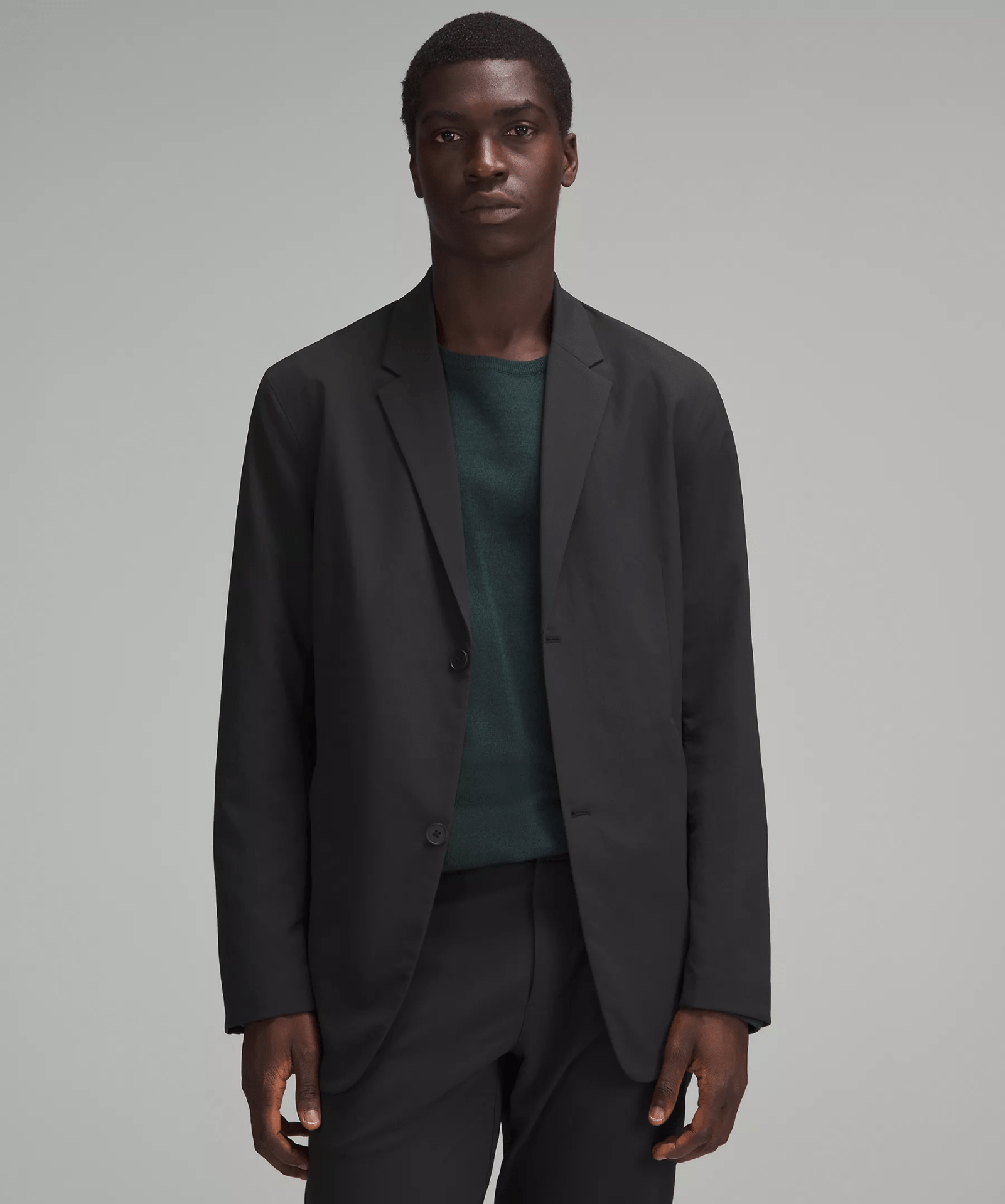 Lululemon New Venture Button-Front Blazer shown in black being worn on a black male model wearing a forest green sweater underneath. 