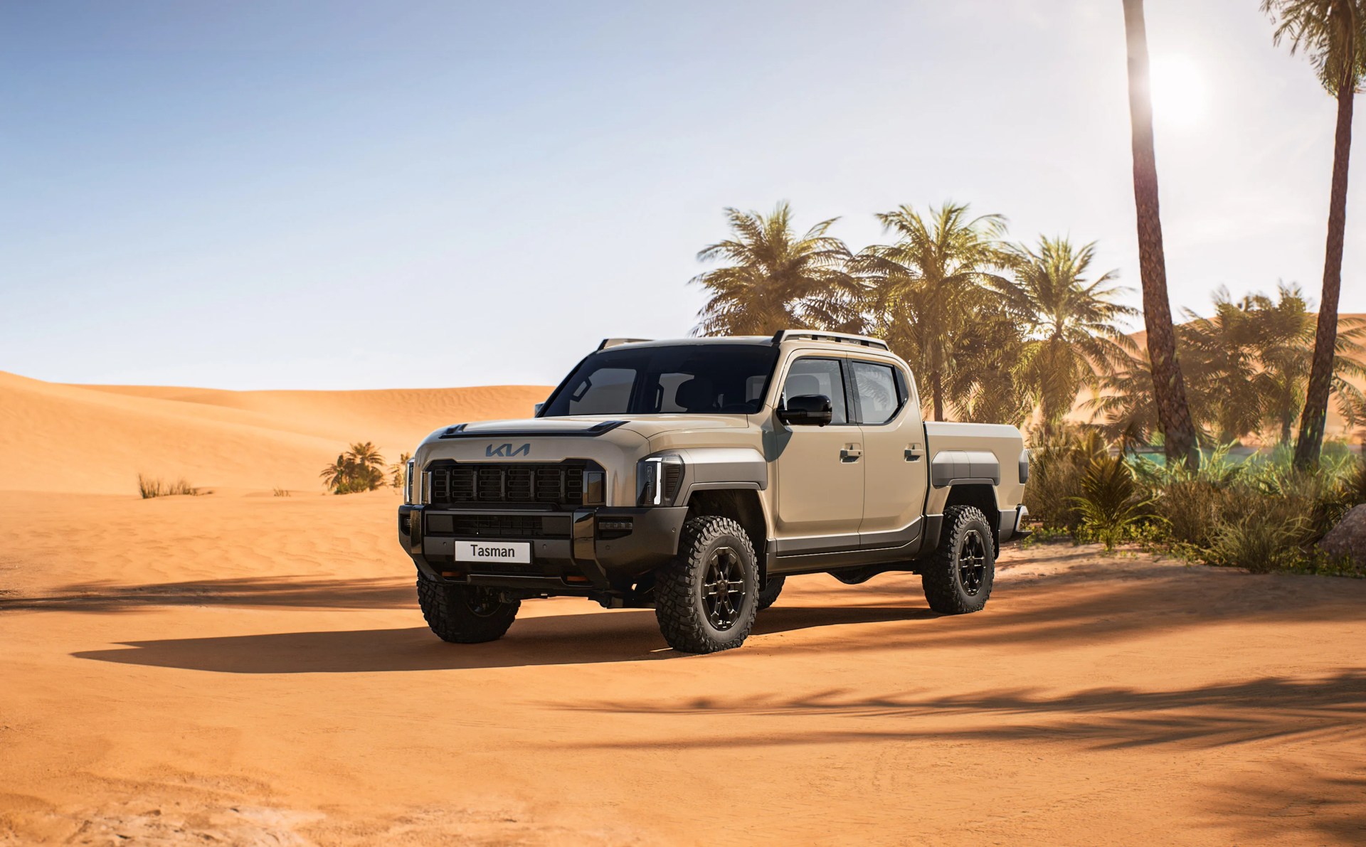 A rendering of the Kia Tasman X-Pro off-roading edition. The truck is shown in a tan color facing forward at an angle in a desert with palm trees and desert shrubs in the background.