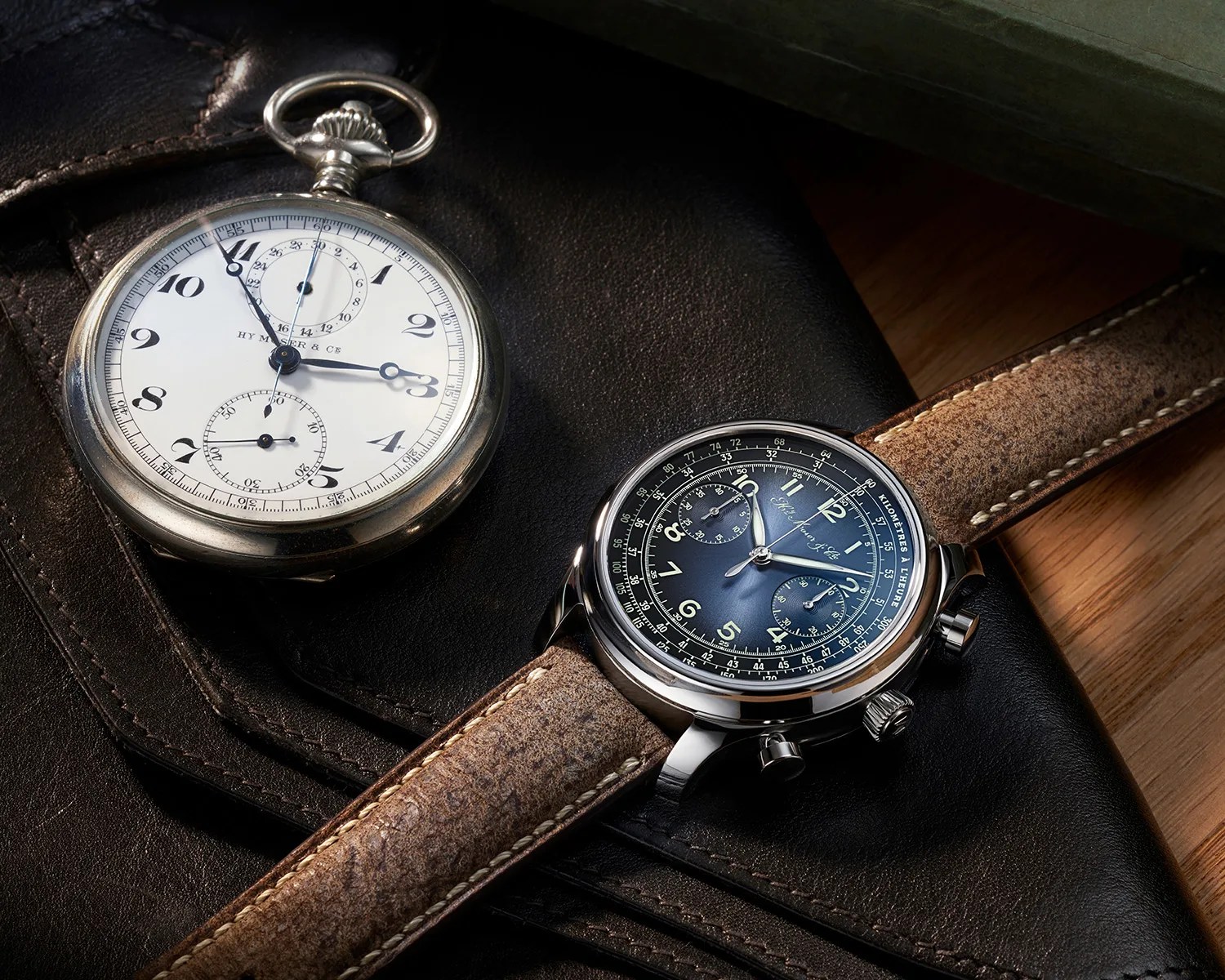 a moser x massena lab watch next to a vintage pocket watch