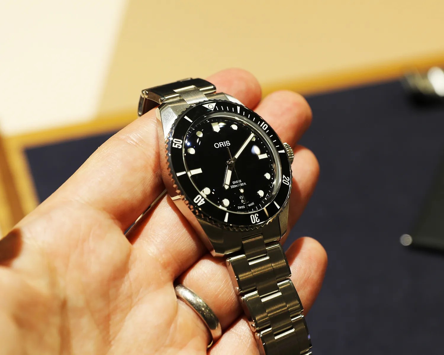 a hand holding an oris dive watch