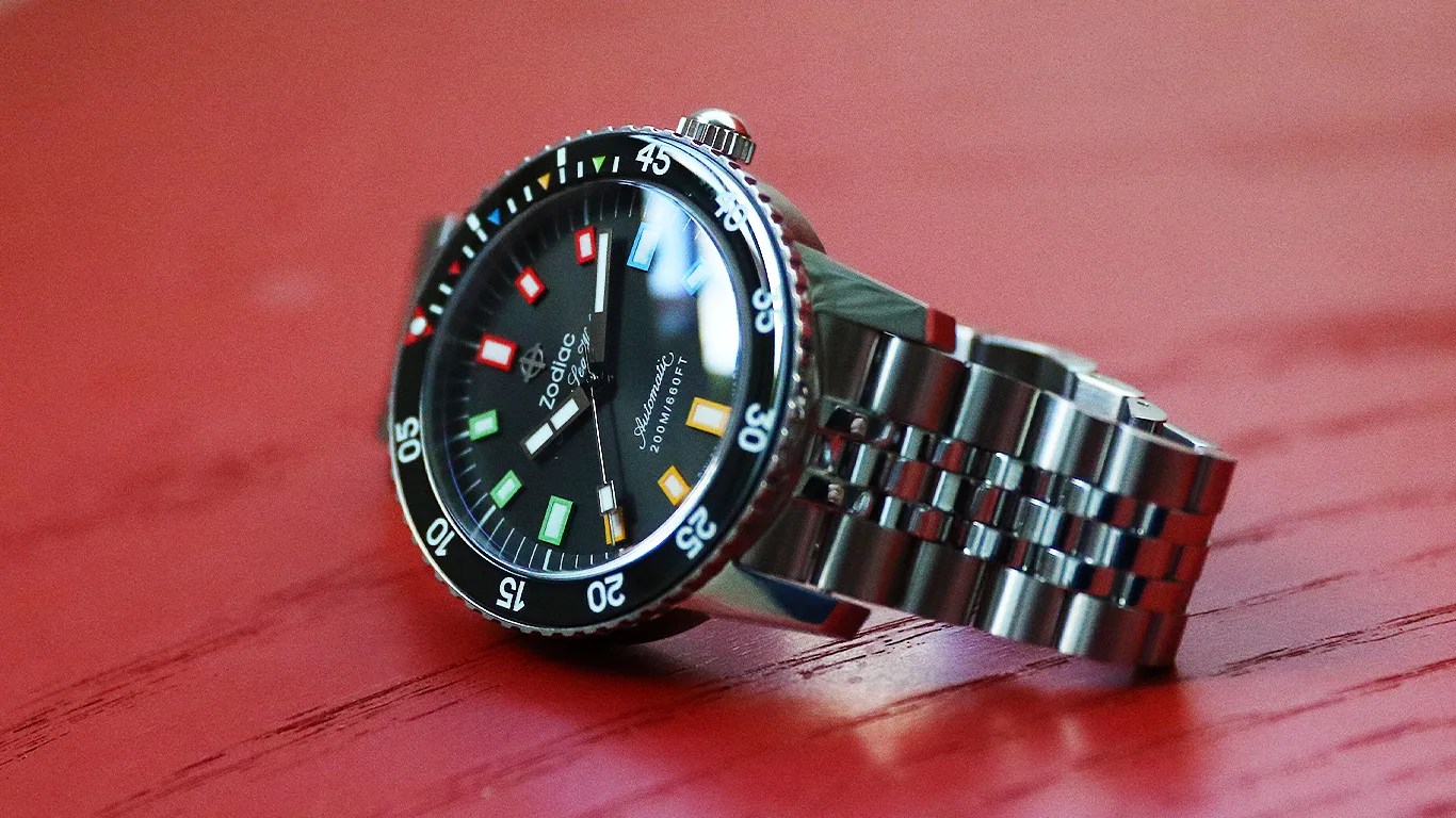 a zodiac dive watch on a red wooden surface