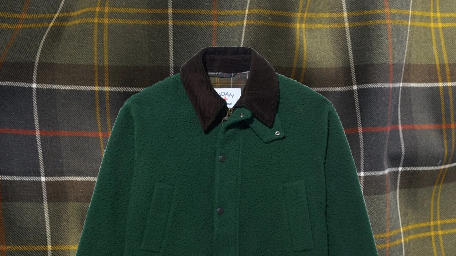 A cut out image of the Barbour x Noah Bedale Jacket in dark fuzzy green sitting on top of a background of Barbour tartan plaid