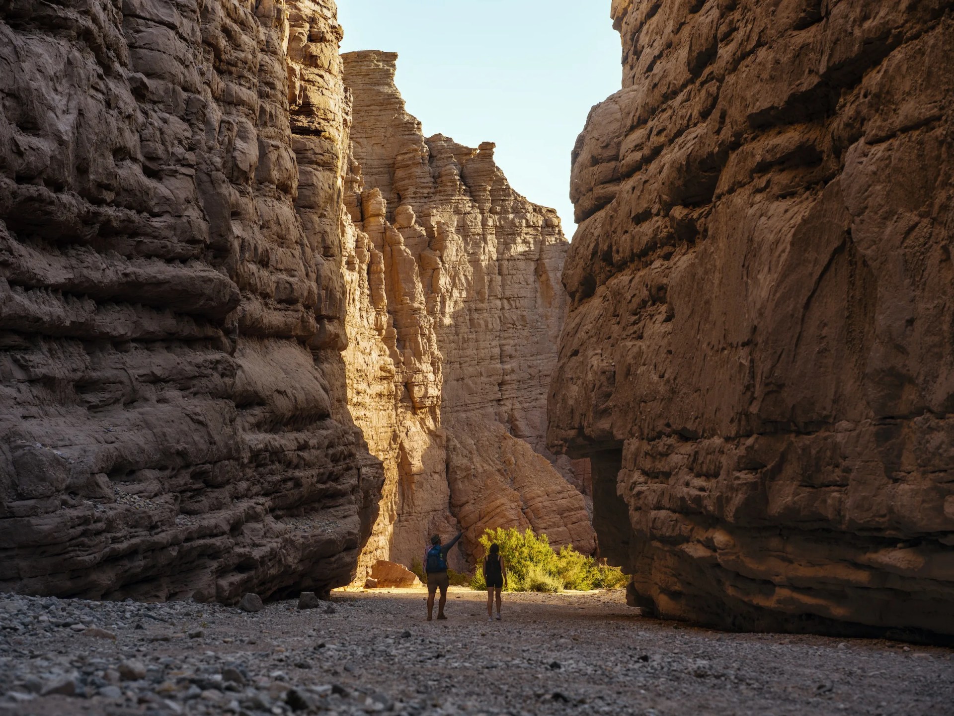Two people hike through a slot canyon