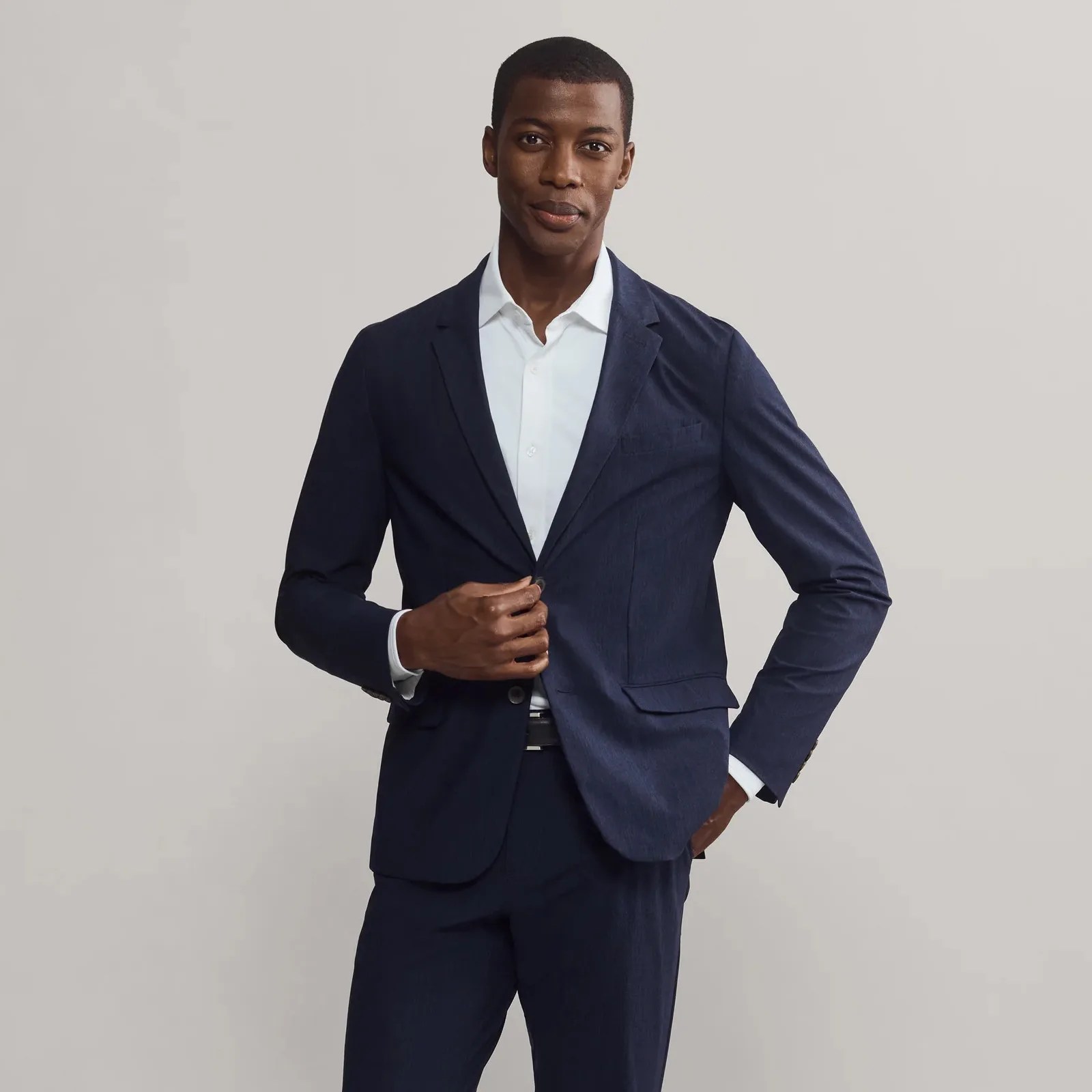 Rhone Commuter Blazer in Navy shown on a black male model wearing a white dress shirt and facing the camera
