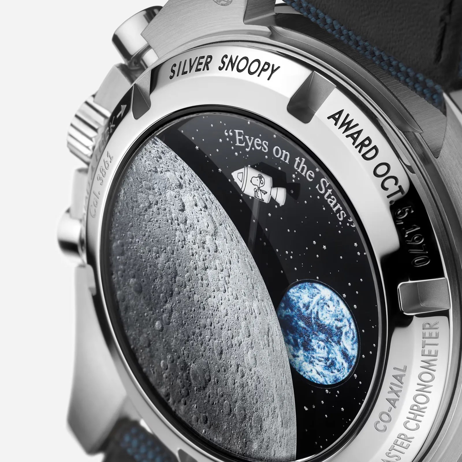 A close up shot of the caseback of the Omega 50th Anniversary edition Silver Snoopy watch. It shows the surface of the moon with the earh in the distance right background. Snoopy appears as a tiny character riding in a white rocket towards the moon. 