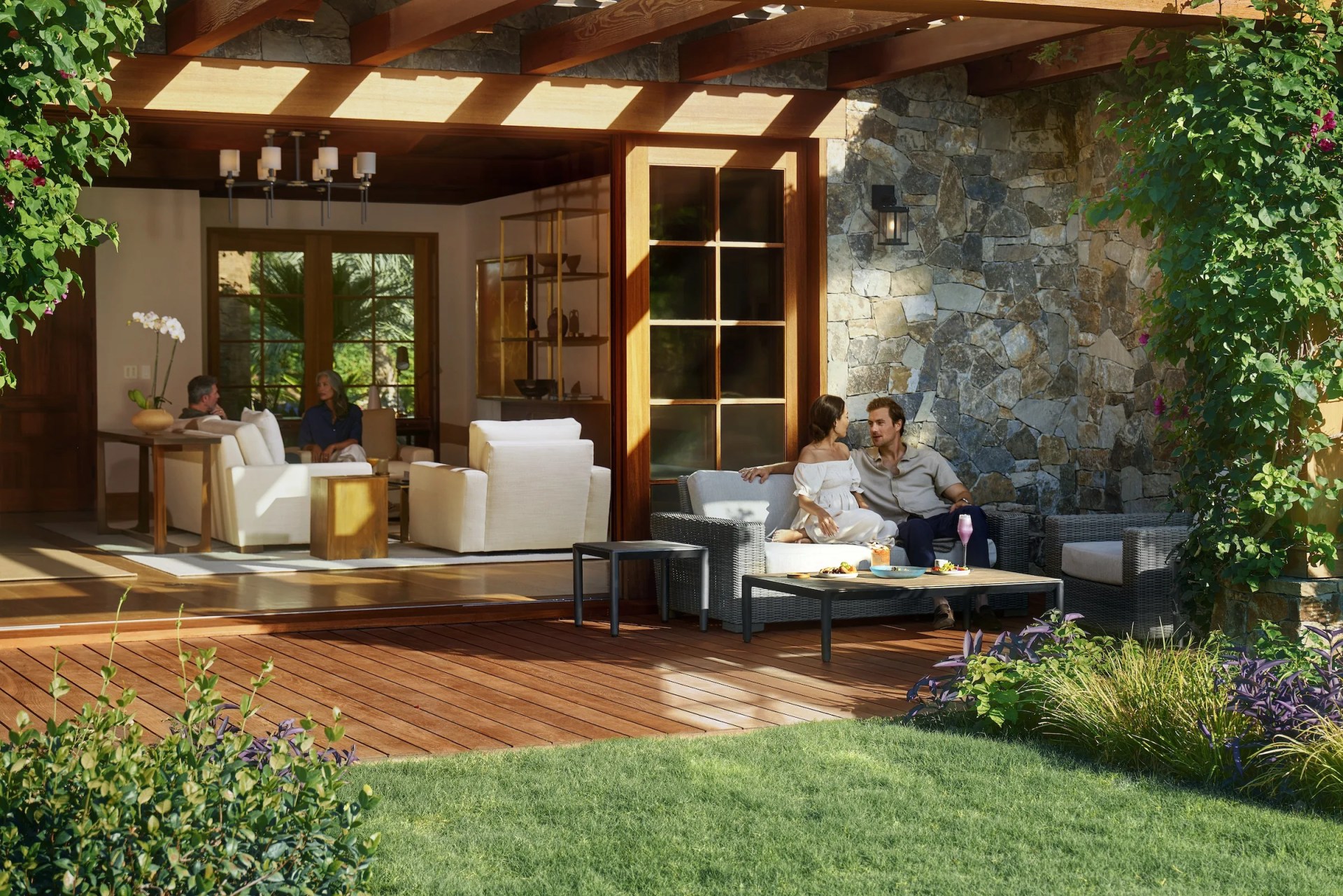 Two people sit on an outdoor couch outside a luxury villa