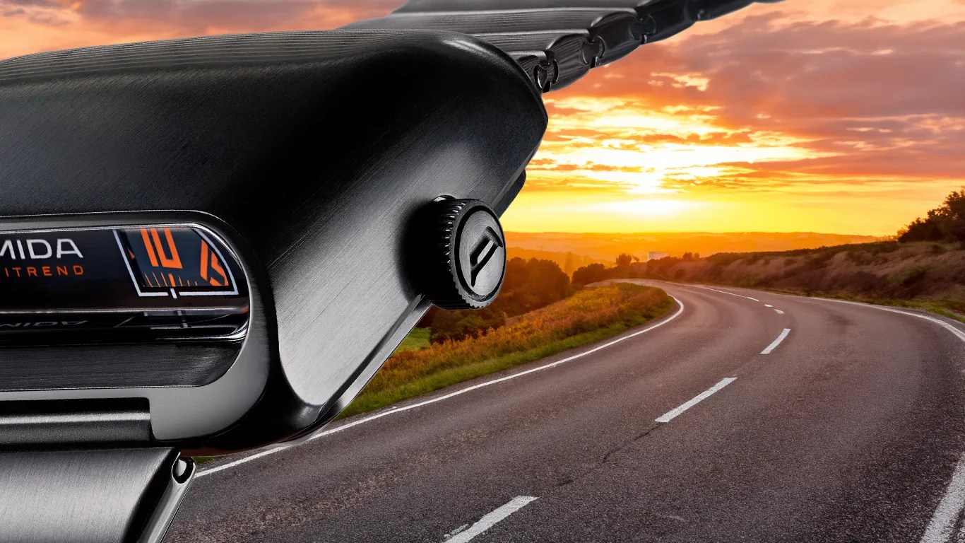 a closeup amida drivers watch superimposed over a winding road