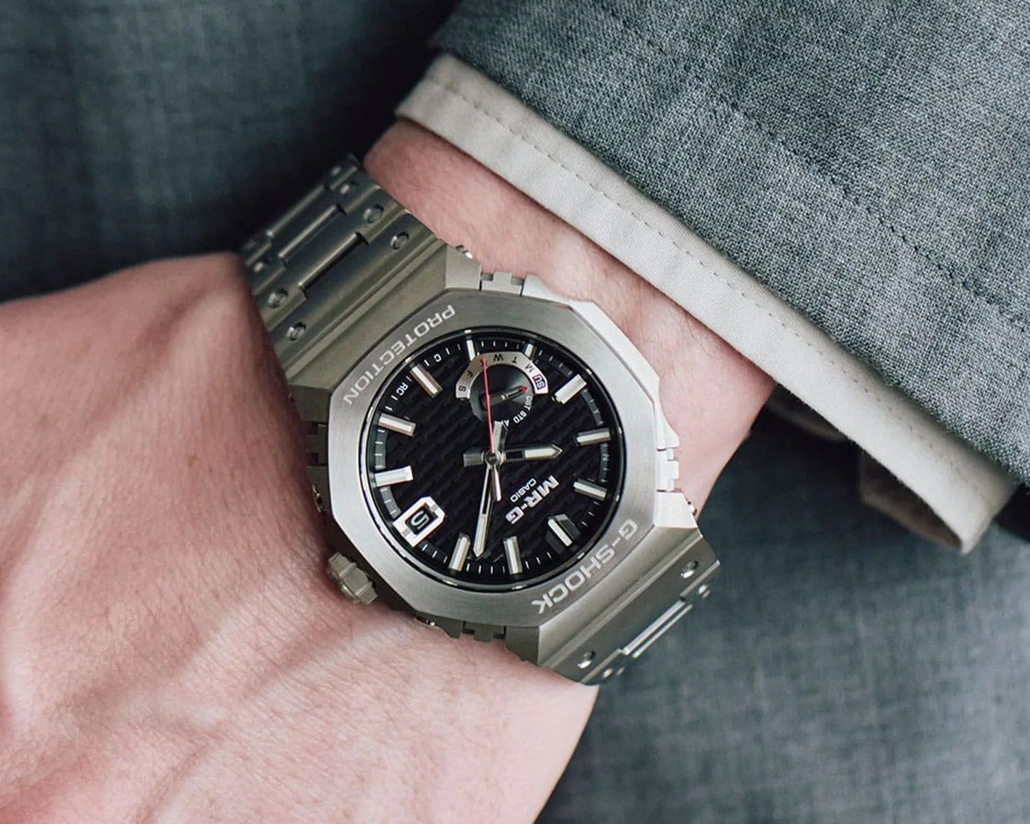 a g shock titanium casioak watch on the wrist of a man wearing a suit