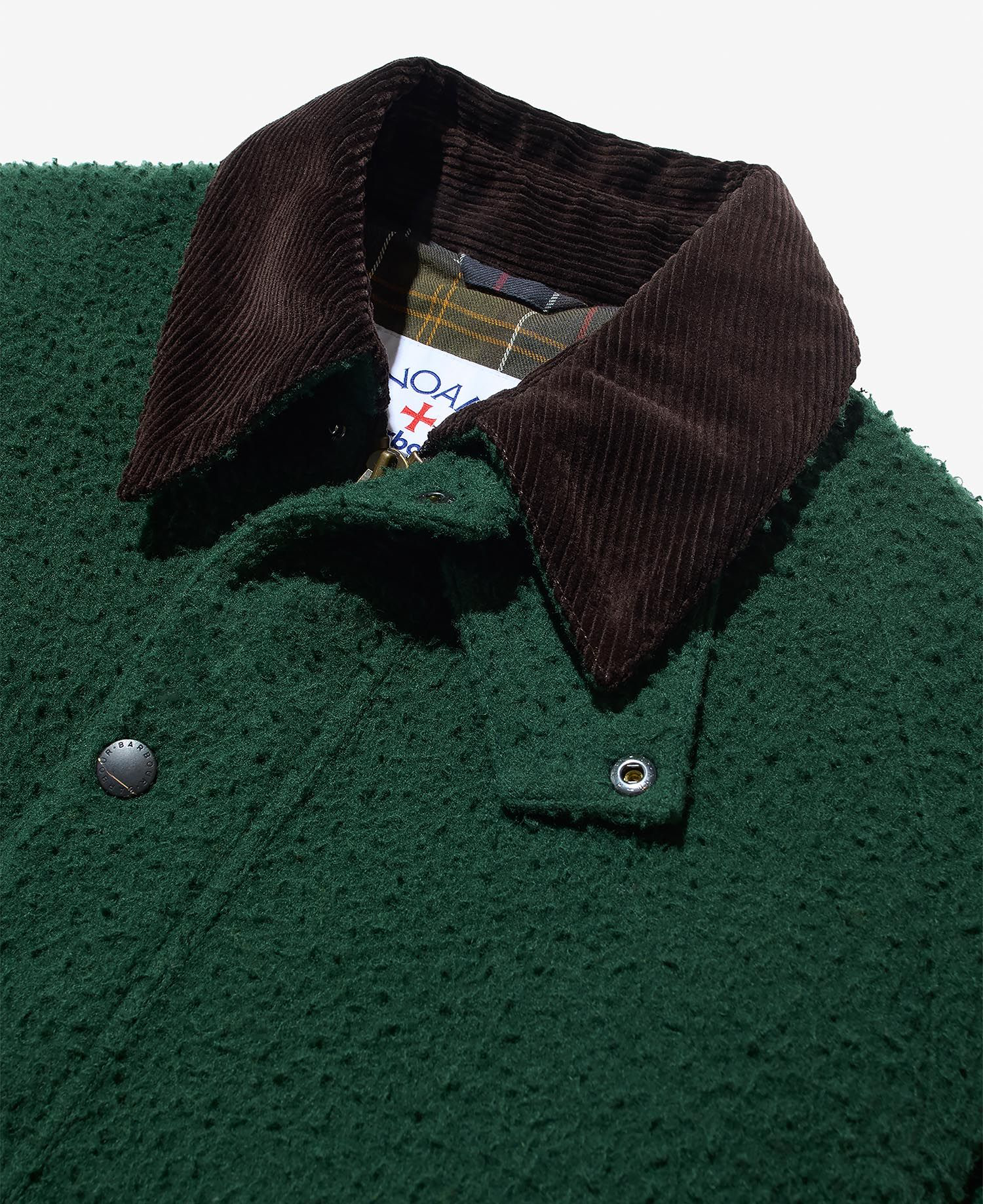 A close up image of the collar and upper shoulder on the Barbour x Noah Wool Bedale Jacket in green. The jacket is lying flat on a light grey background.