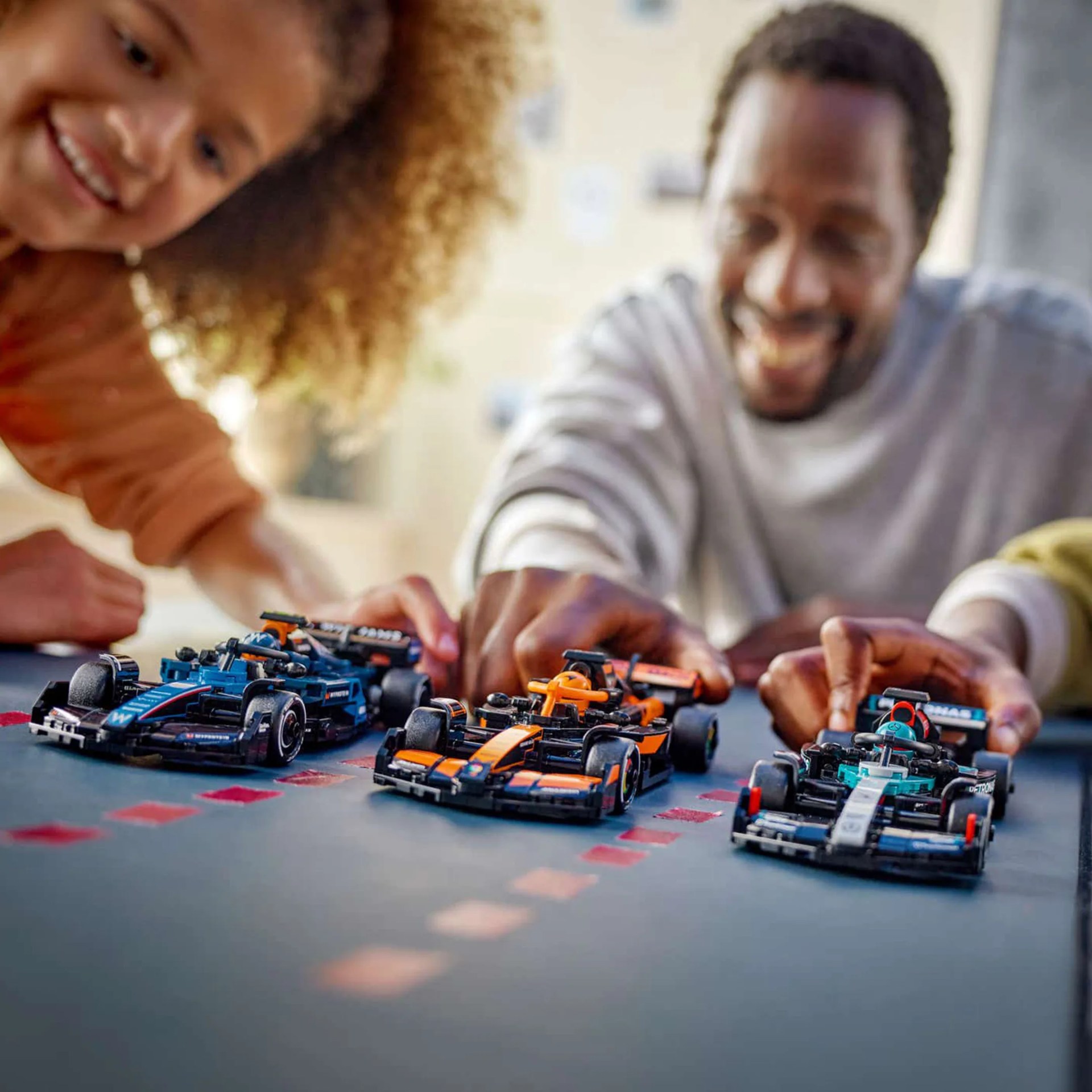 a father and dauther play with lego formula one cars