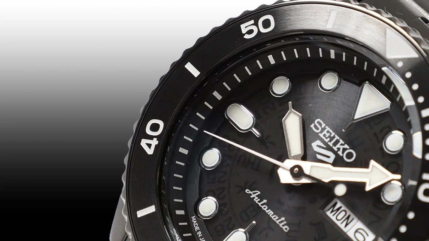 a closeup of a seiko x beams watch dial against a black gradient background