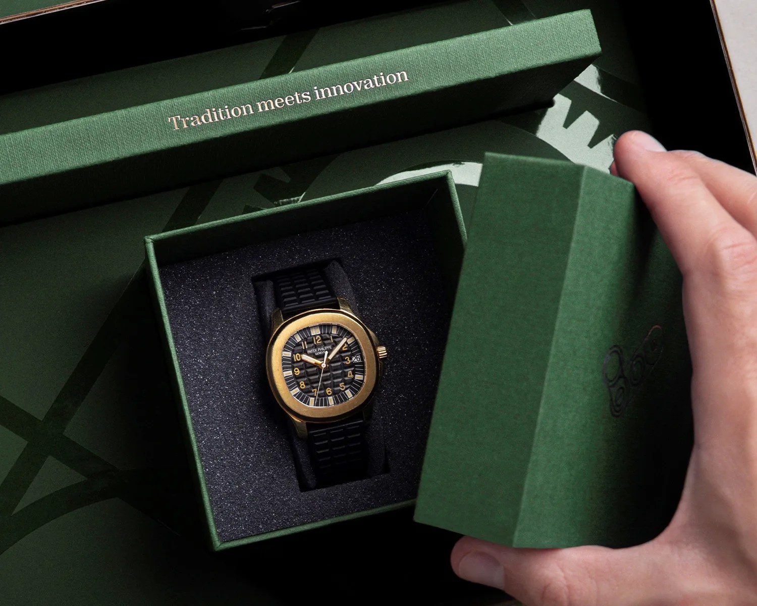 a person opens a watchcheck box to reveal a gold patek philippe aquanaut watch
