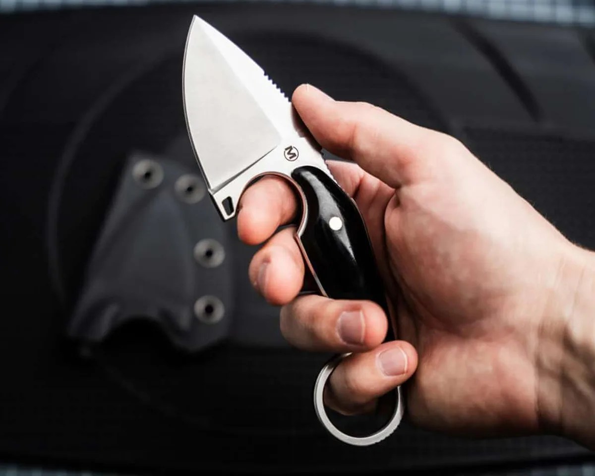 Böker Magnum Enki held in a hand over a black blurry background