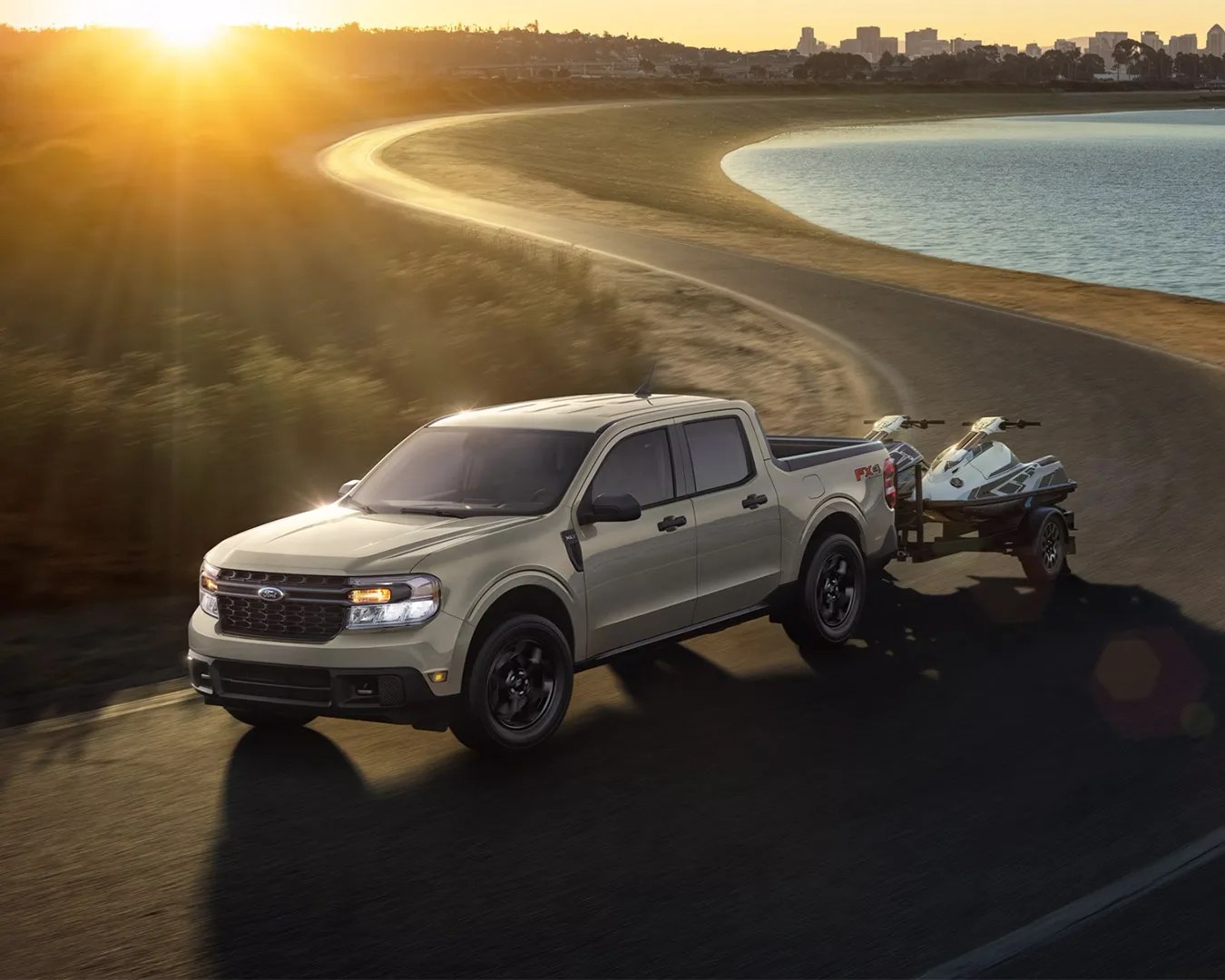 Ford Maverick Hybrid car driving on road with two jet skis attached to the back