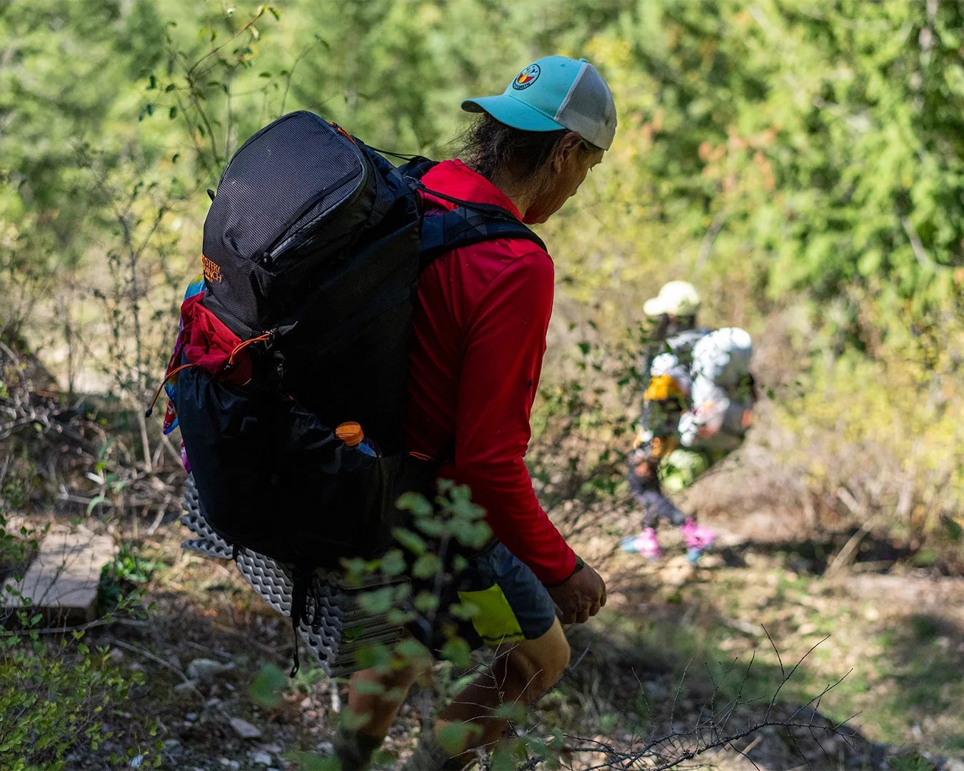 man hiking down hill wearing Mystery Ranch Radix 57 Backpack