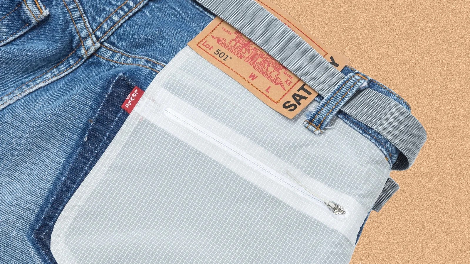 A close up of the back right pocket made of dyneema and belt on a pair of Levi's 501 re-possessed climb jeans shown laid flat against a speckled tan background