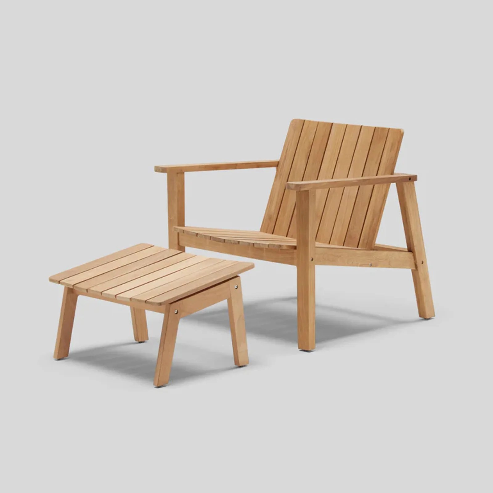 The Neighbor Low Chair and Ottoman in teak wood shown at an angle against a dark gray background