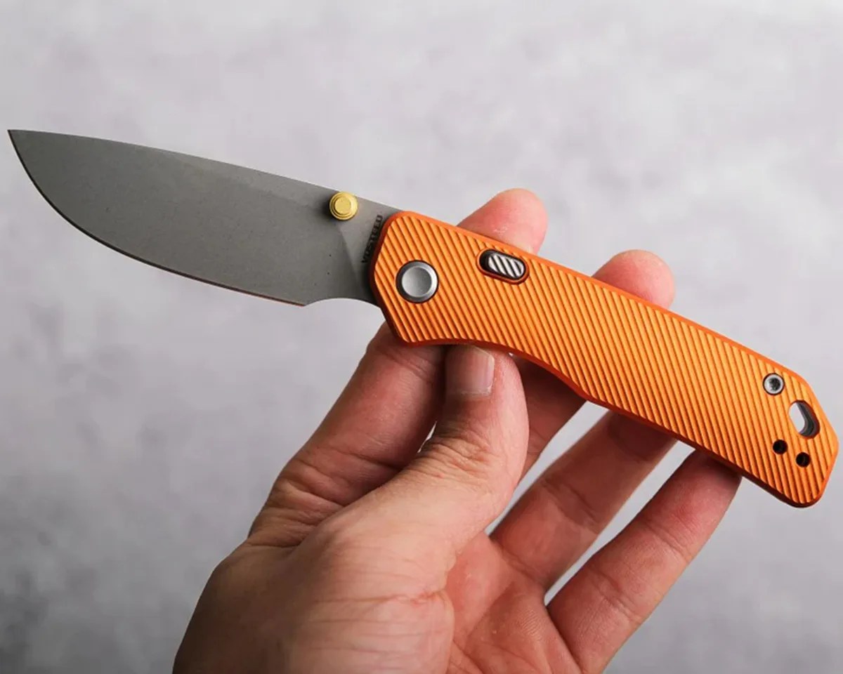 Hand holding Vosteed Marten Knife above gray background