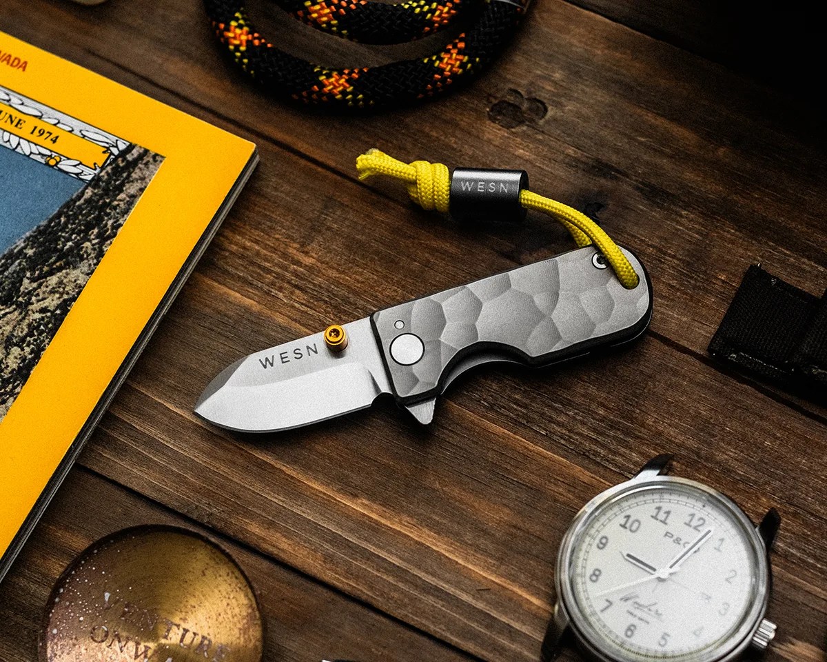 WESN Ridgeback Microblade on wood table surrounded by rope, watch, magazine