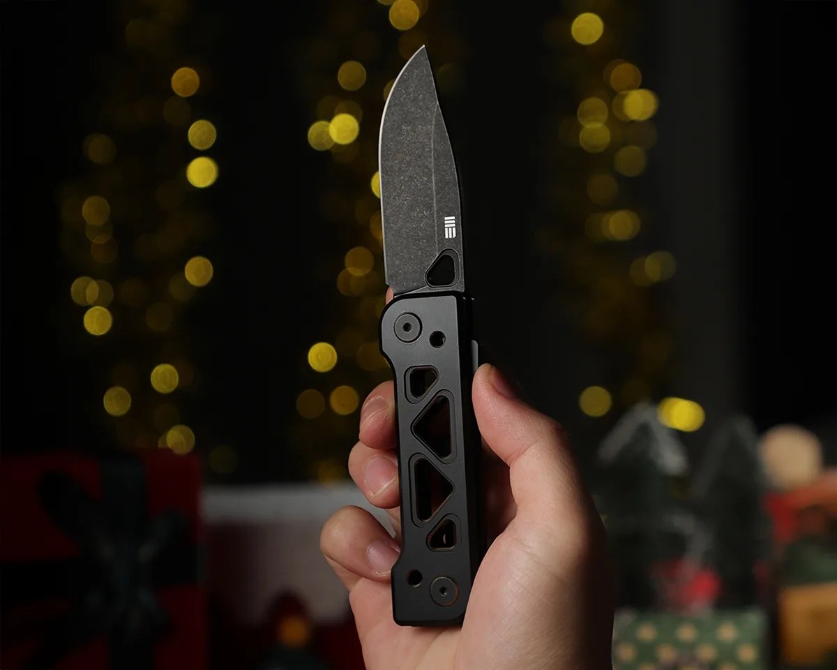 We Knife Tyro in someone's hand in front of blurry decorative lights