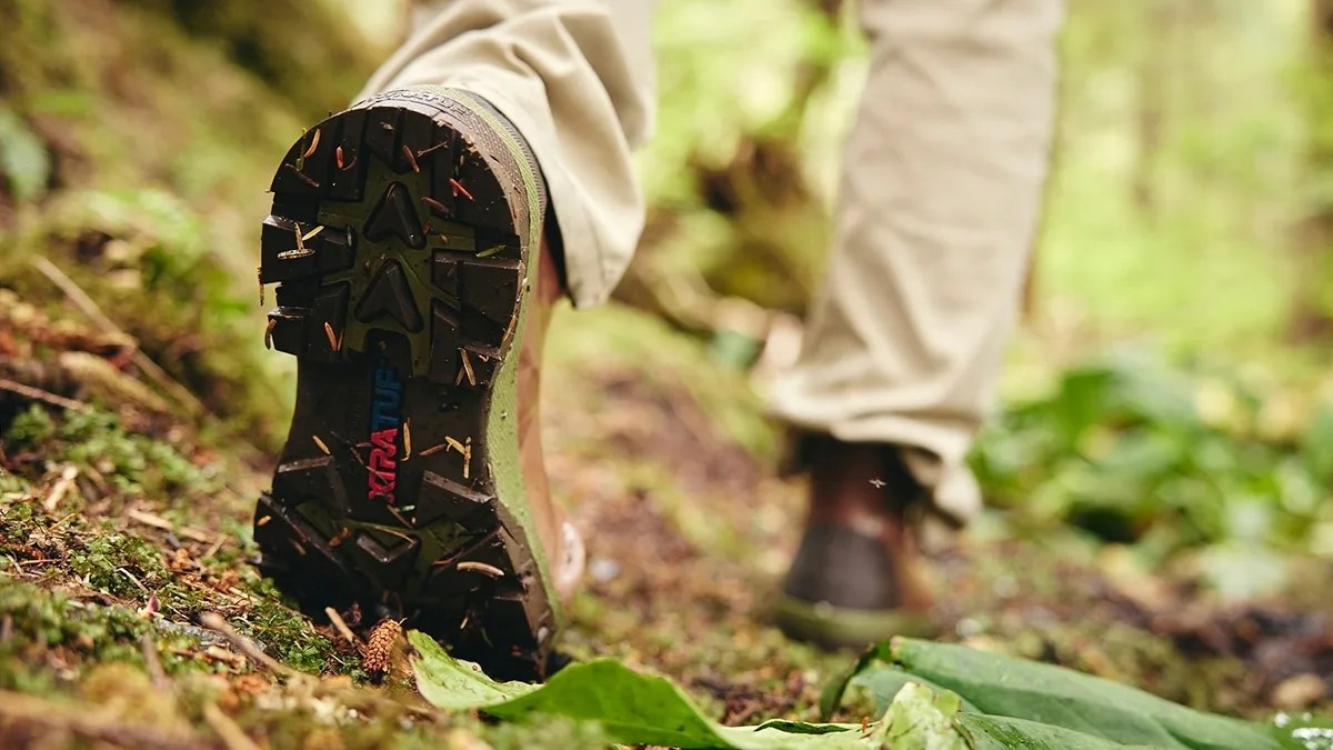 Person walking up mossy hillside wearing Xtratuf Legacy Altitude Low boots