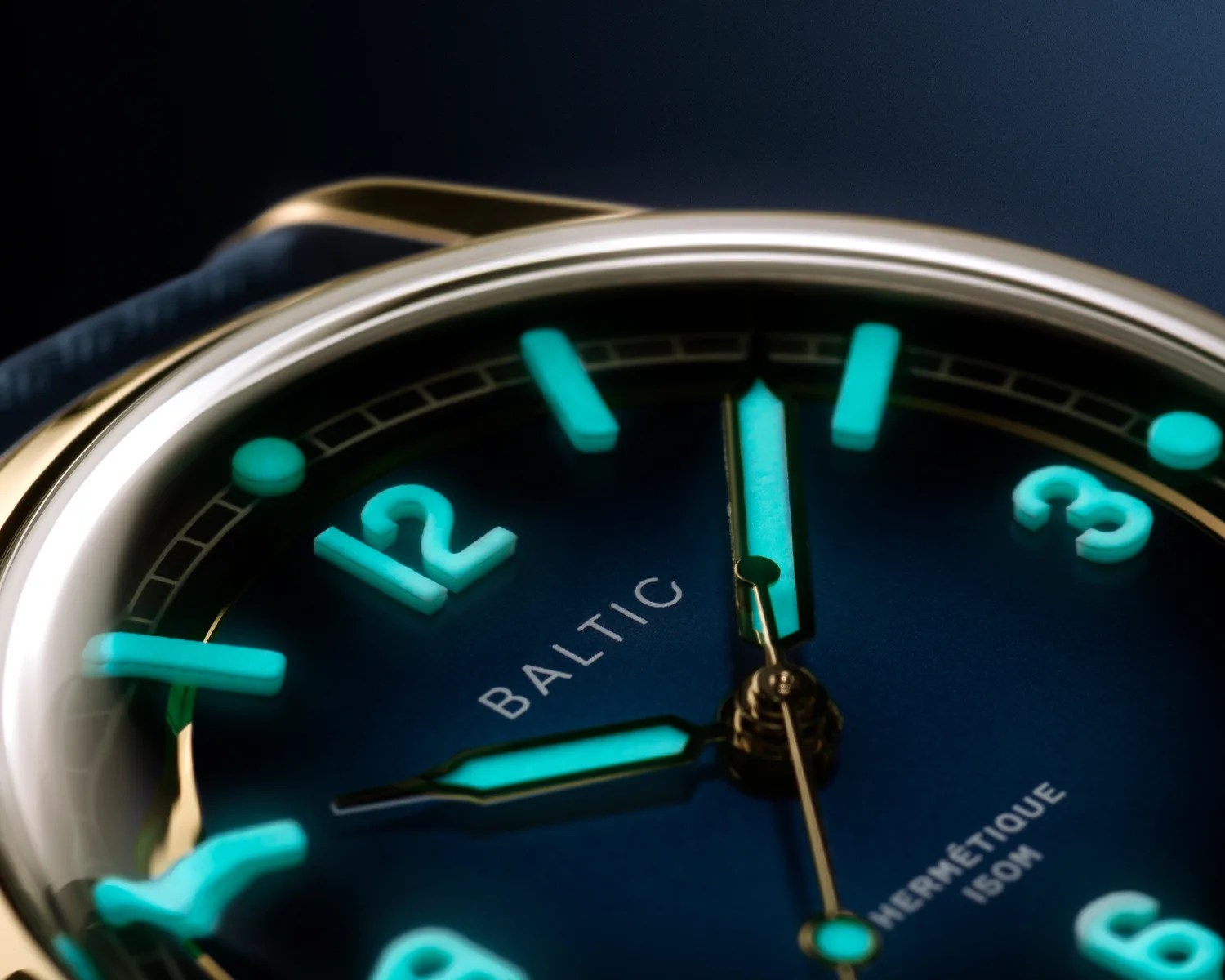 a close up of a baltic watch dial with lume glowing