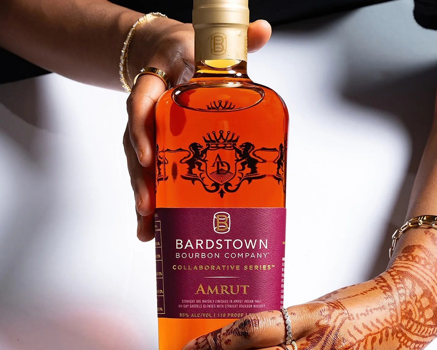 a woman with henna tattoos holds a bottle of bardstown bourbon company whiskey