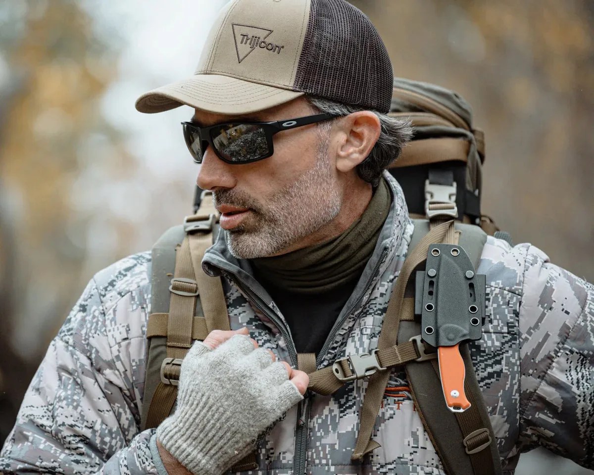 man carrying Civivi knife with orange handle on his backpack strap