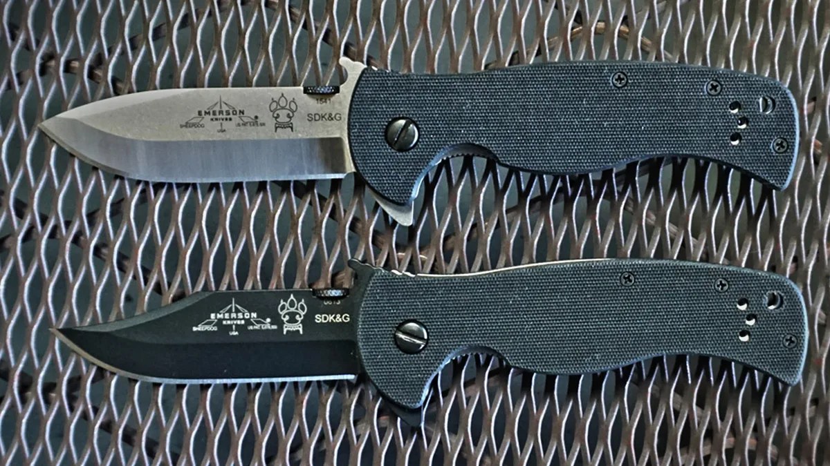 Two Emerson Sheepdog folding knives sitting on metal grate
