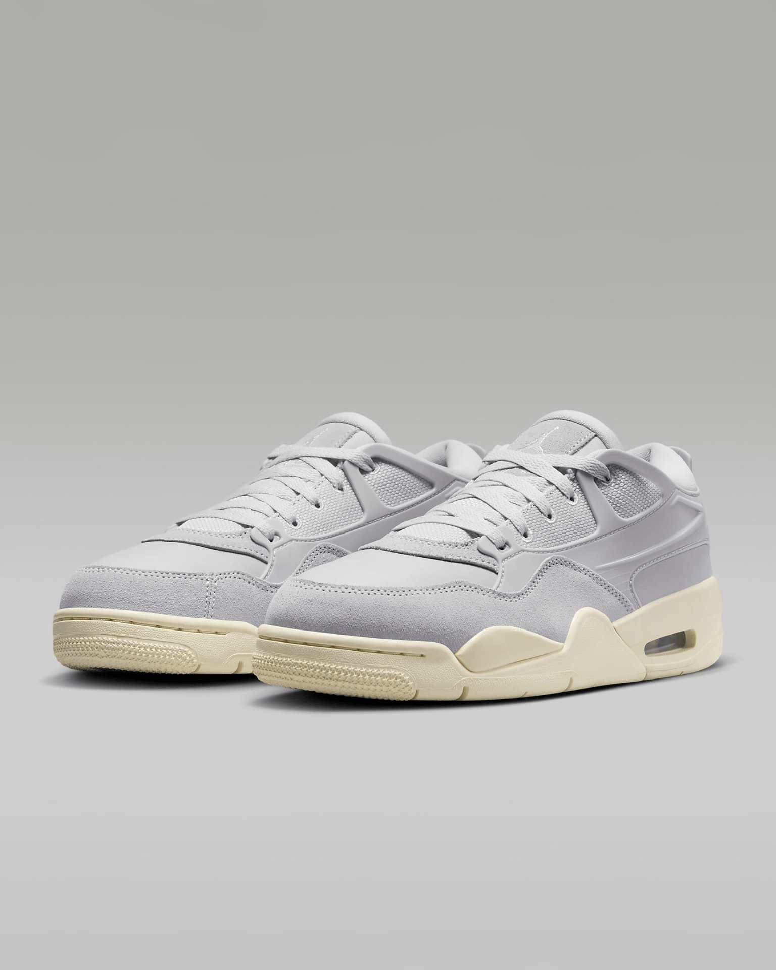 An image of all grey Air Jordan RM4's shown at an angle against a light grey background. The outsoles of the shoe are light cream. 