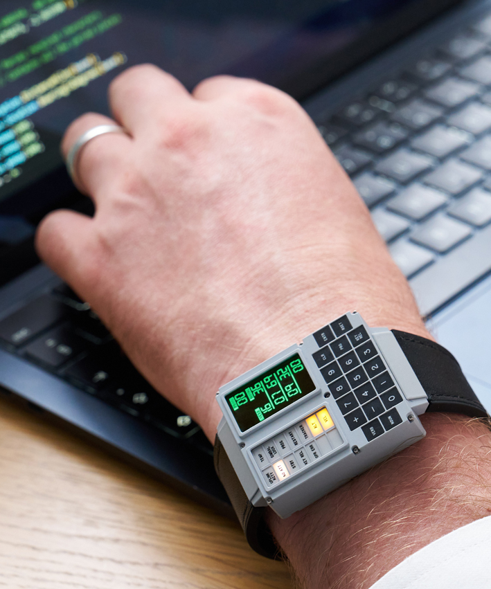 The Apollo Instruments DSKY Moonwatch shown being worn on a mans wrist. The hand and wrist are shown typing on a laptop keyboard