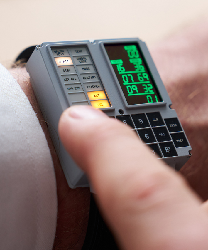 The Apollo Instruments DSKY Moonwatch shown being worn on a wrist with a finger reaching out to press one of the watch's buttons. 